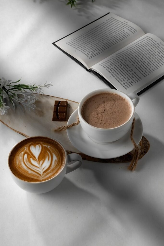 coffee, hot chocolate, latte art, book, chocolate, light, café, relaxation, reading, coziness, aroma, warm, wooden tray, calm atmosphere, white color, natural materials, comfort, board